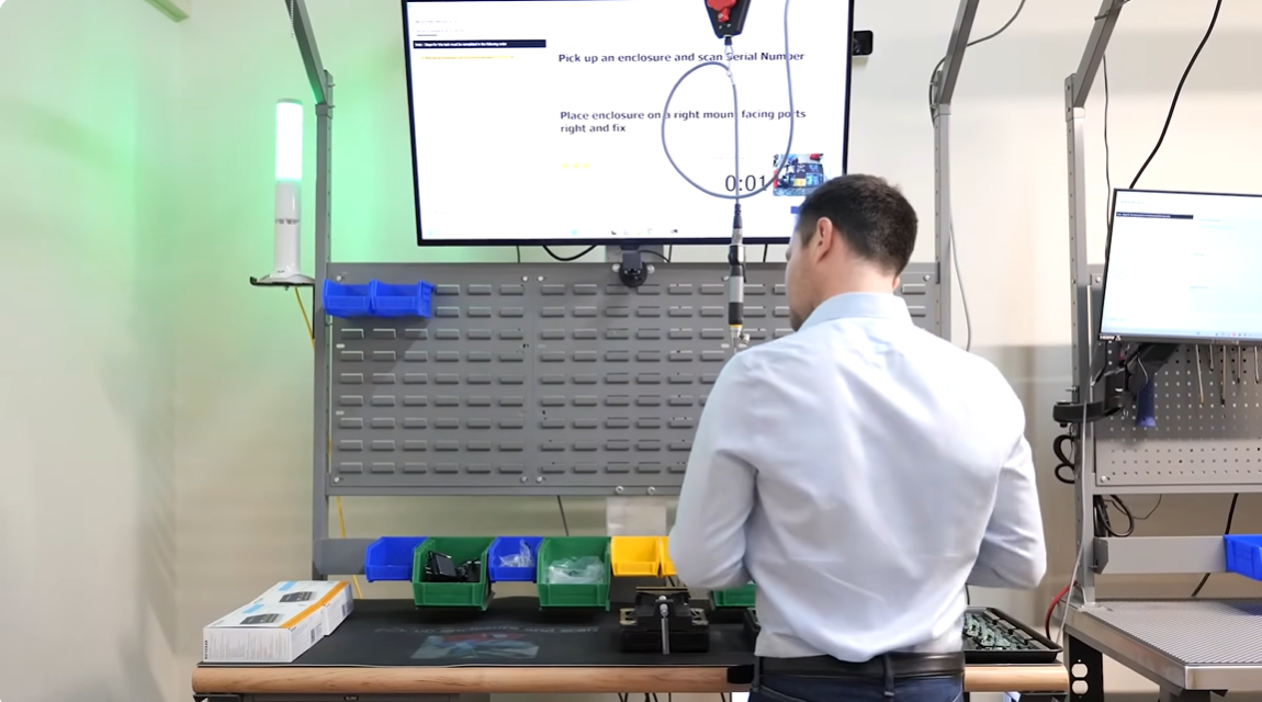 Operator interacting with digital SOP instructions and serial barcode scanner on workstation display